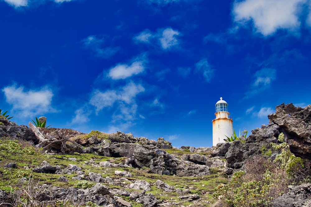 a light house on a rocky hillside under a blue sky