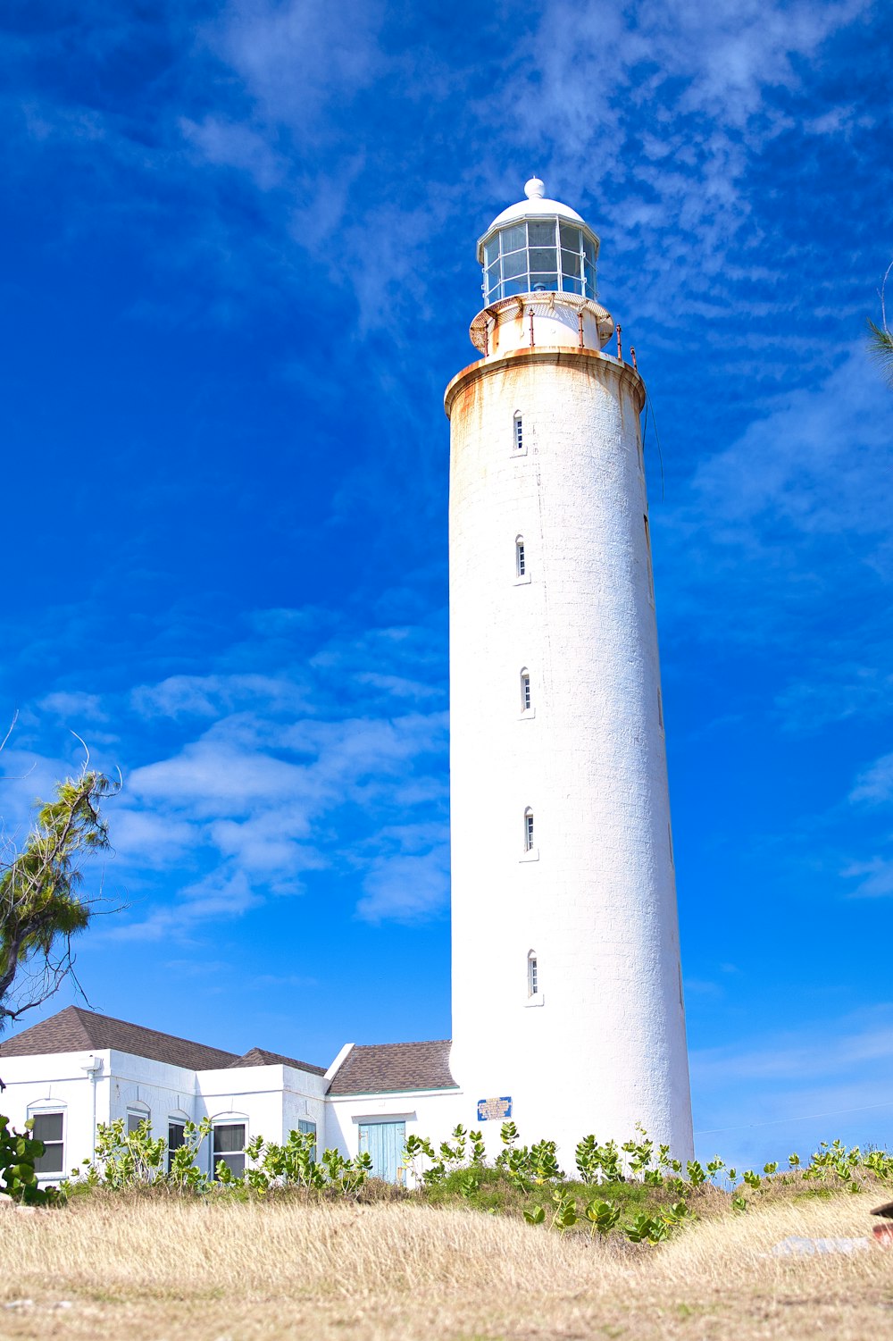 a white light house sitting on top of a hill