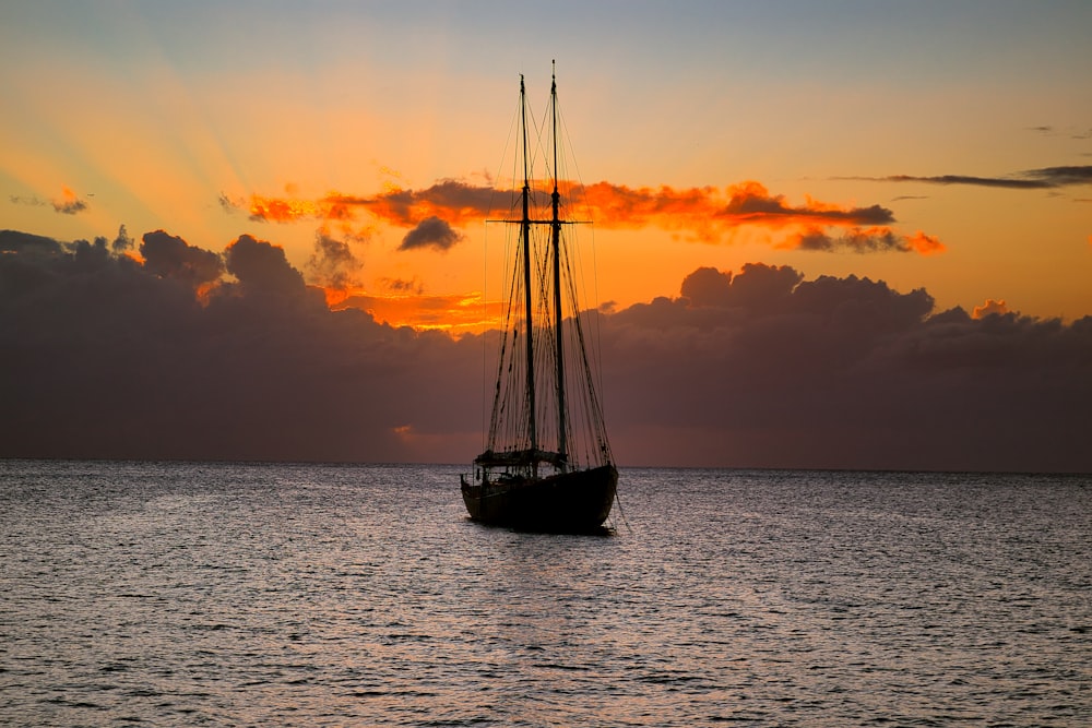 a sailboat floating in the ocean at sunset