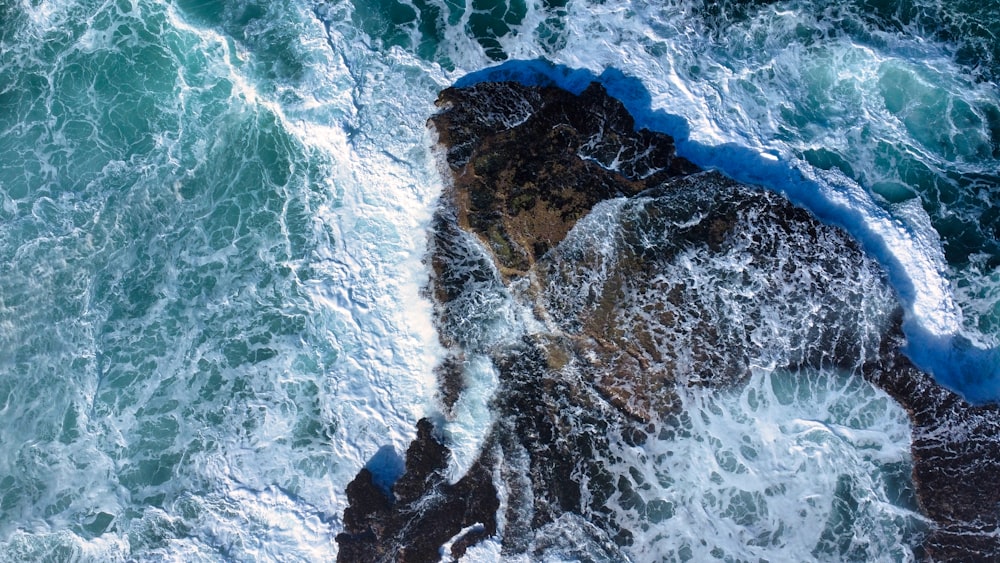 an aerial view of the ocean and rocks