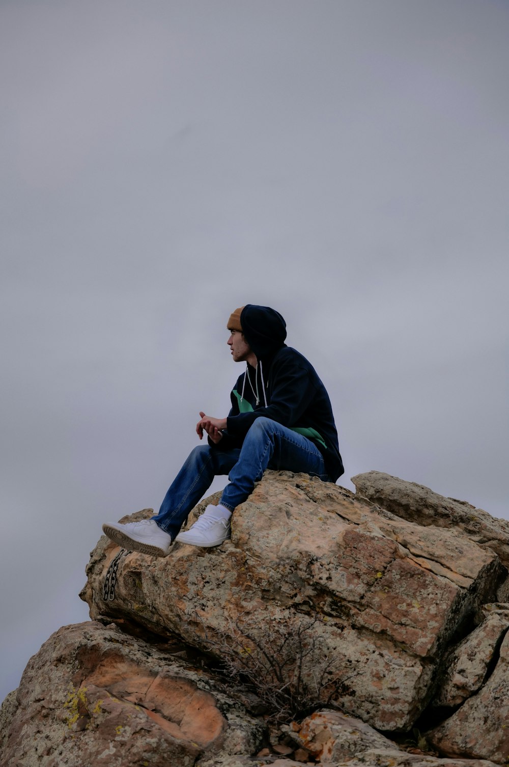 a man sitting on top of a large rock