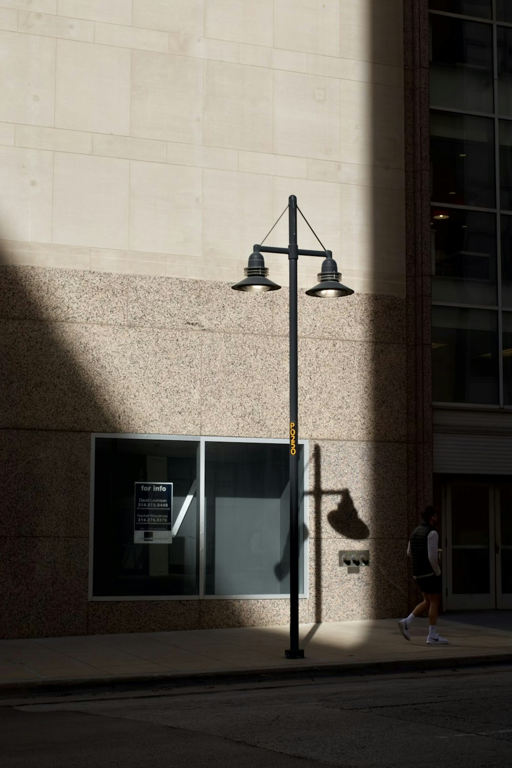 a person walking down a street past a tall building