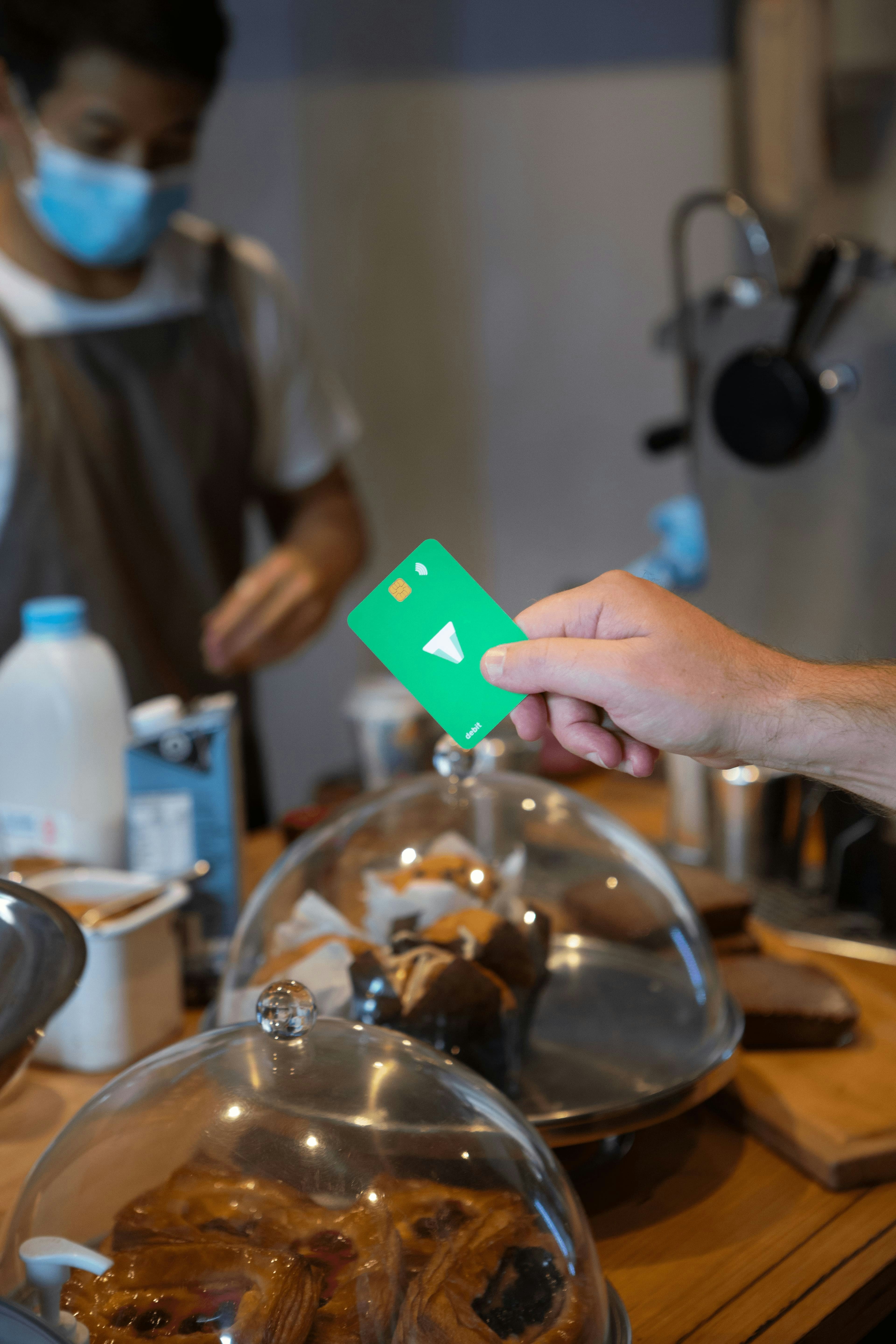 eine Person, die eine Gesichtsmaske trägt und eine Green Card besitzt