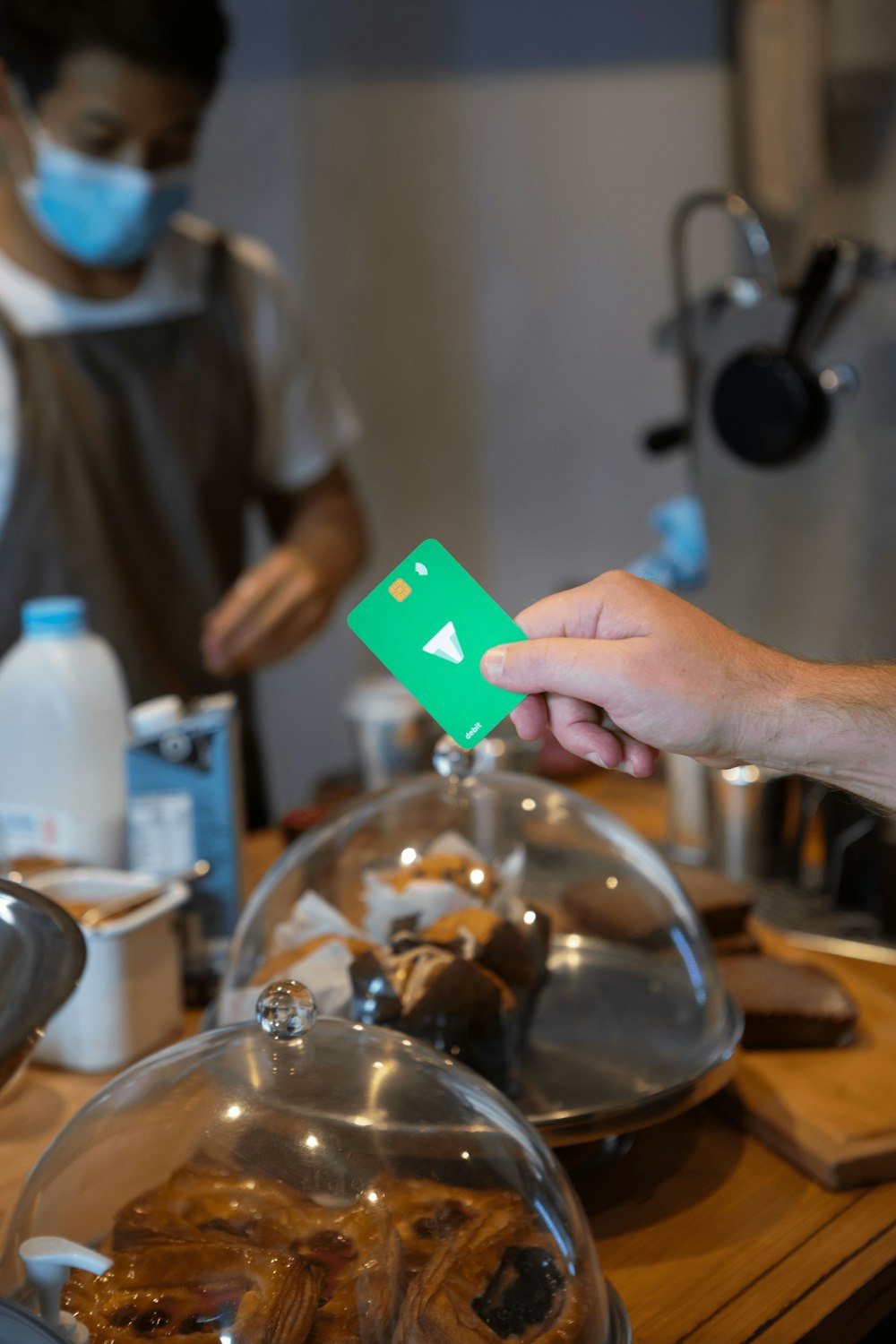 a person wearing a face mask and holding a green card