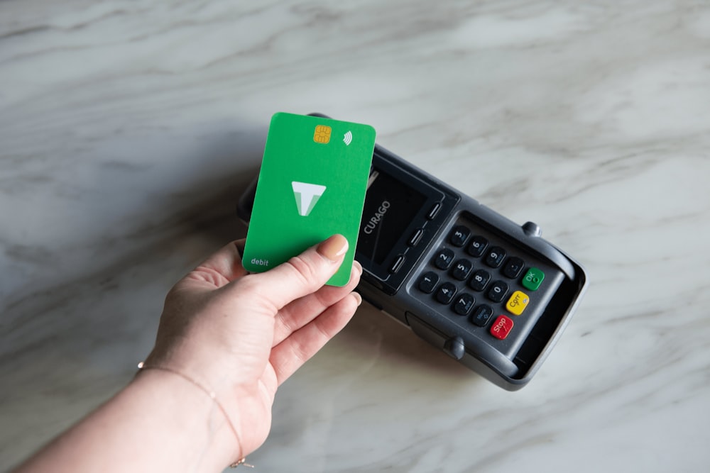 a hand holding a green card next to a calculator
