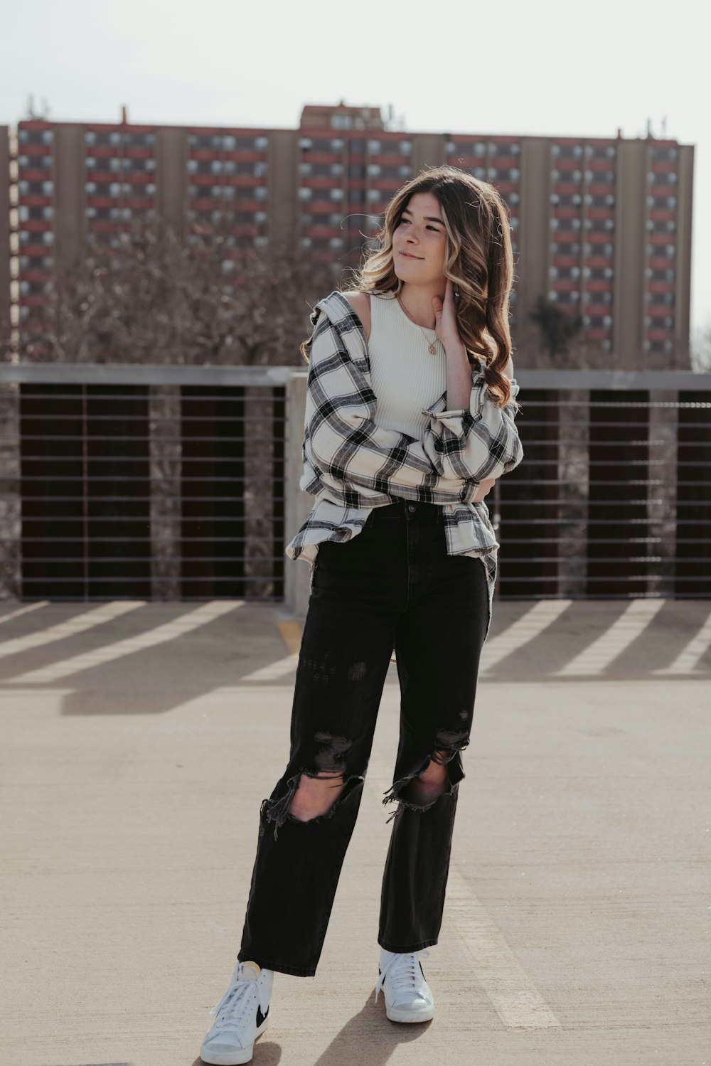 a woman standing in a parking lot with her arms crossed