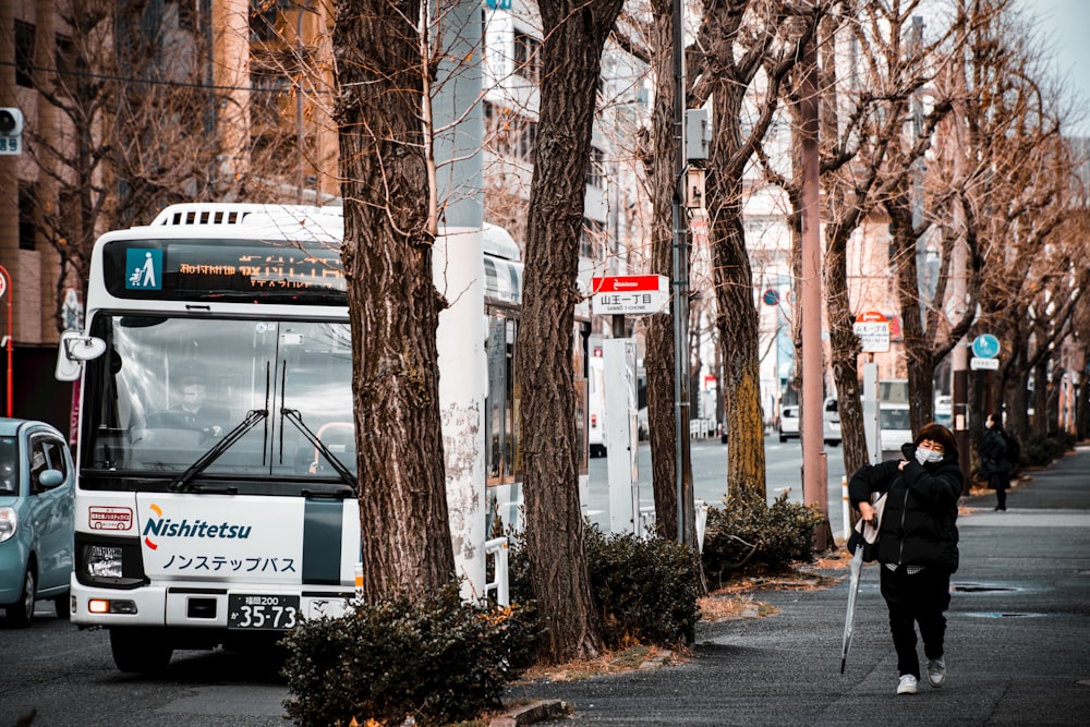 a man walking down a street next to a bus