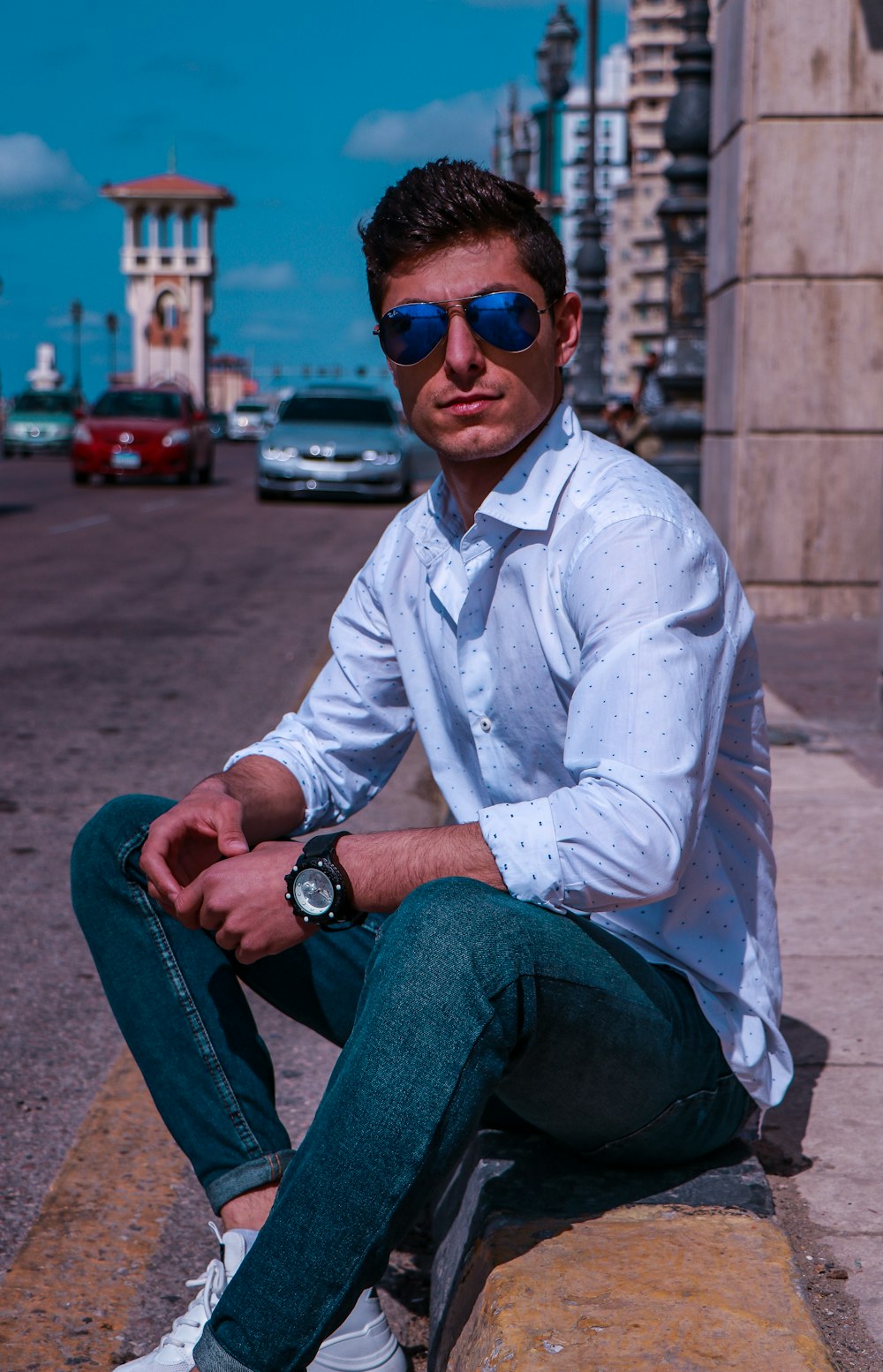 a man sitting on a ledge wearing sunglasses
