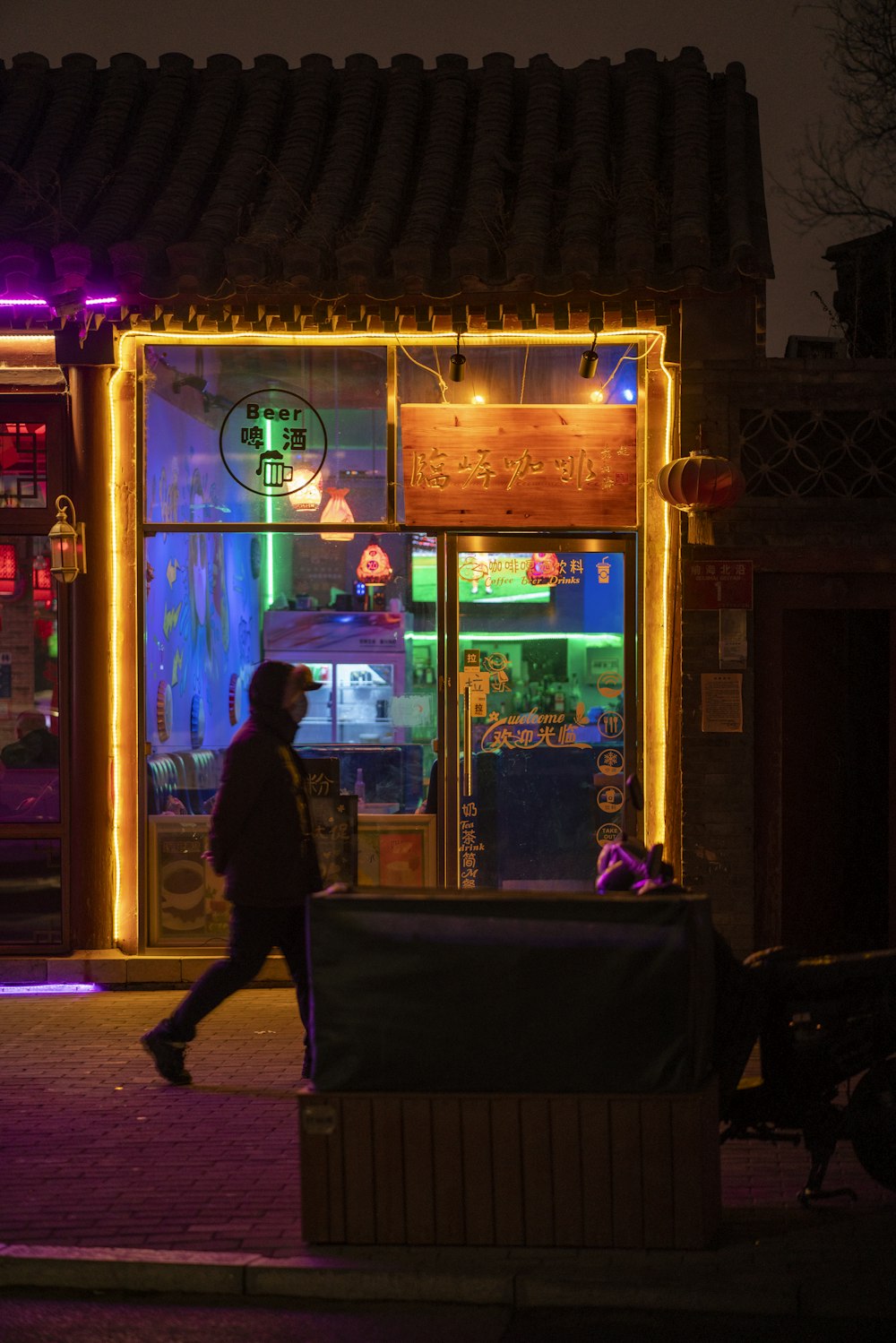 a man walking past a store front with lights on it