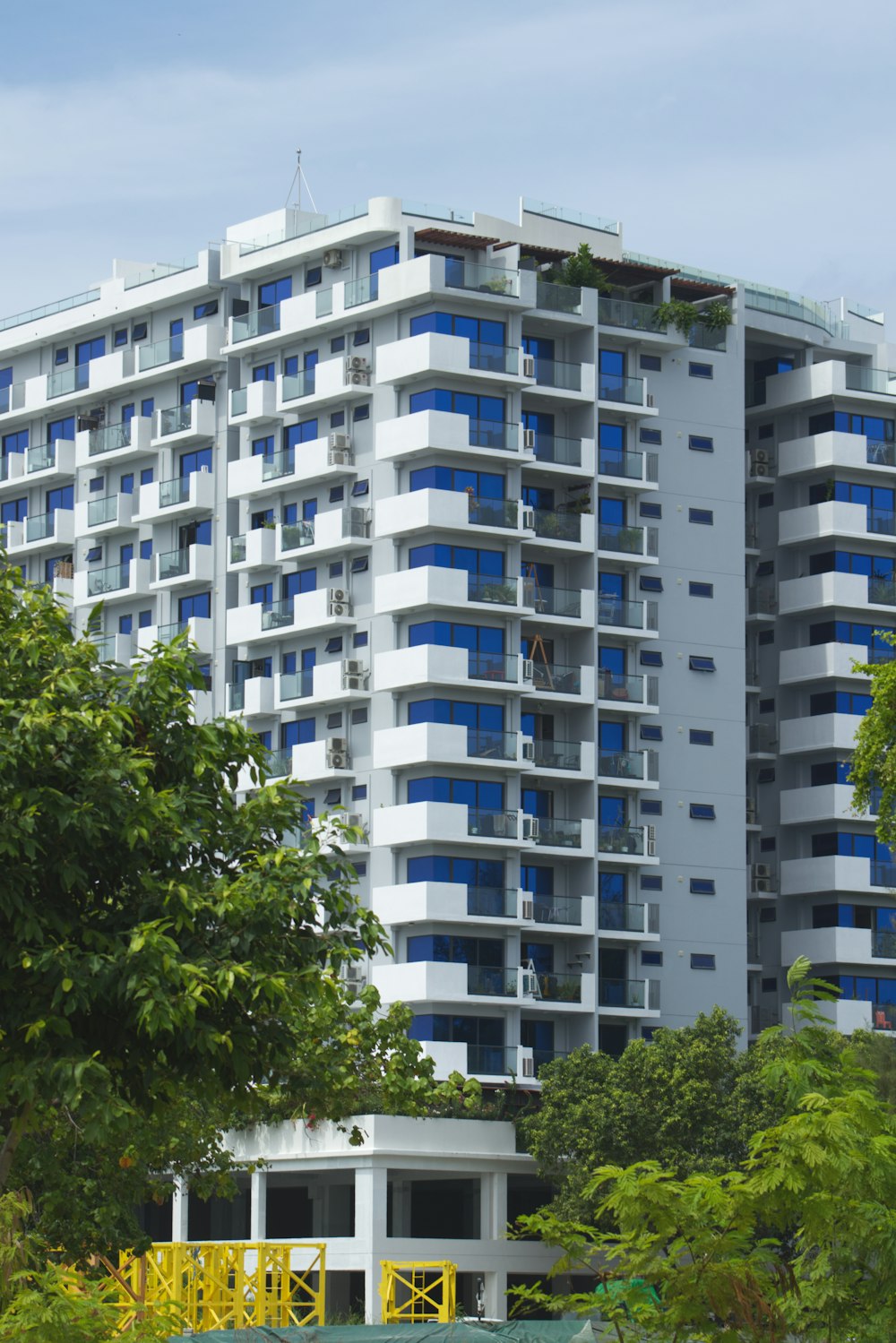 a tall white building with blue windows next to trees