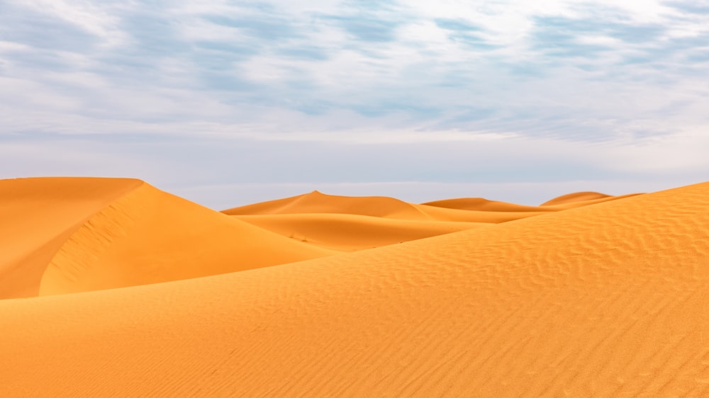 a group of sand dunes under a blue sky