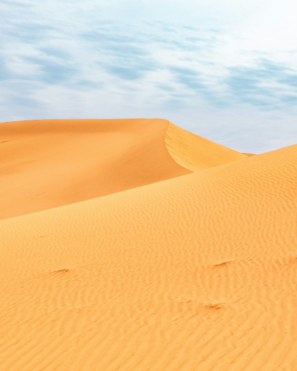a person walking across a desert with footprints in the sand