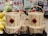 A stack of woven bamboo baskets with handles, displayed in a market. Each basket has a red diamond-shaped label featuring Chinese characters. Surrounding the baskets are signs indicating prices in various currencies and informational signage mostly in Chinese. To the left, there are green and yellow oversized pomelos, adding to the market setting.