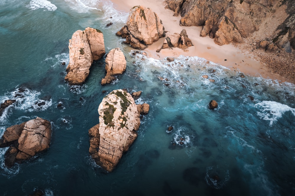 an aerial view of a beach with rocks and water