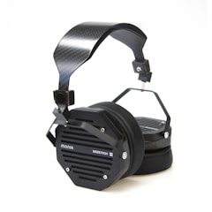 A pair of black over-ear headphones featuring a modern, industrial design with a carbon fiber headband and hexagonal earcups labeled with 'Mania' and 'Erzetich'. The earcups are equipped with metal grilles and sturdy connectors, giving a sleek and robust appearance.