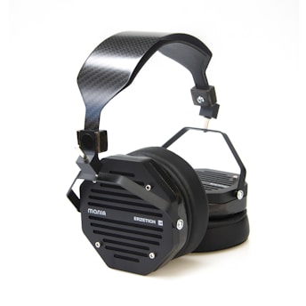 A pair of black over-ear headphones featuring a modern, industrial design with a carbon fiber headband and hexagonal earcups labeled with 'Mania' and 'Erzetich'. The earcups are equipped with metal grilles and sturdy connectors, giving a sleek and robust appearance.