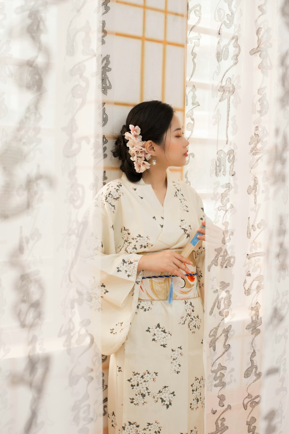 a woman standing in front of a window with a flower in her hair