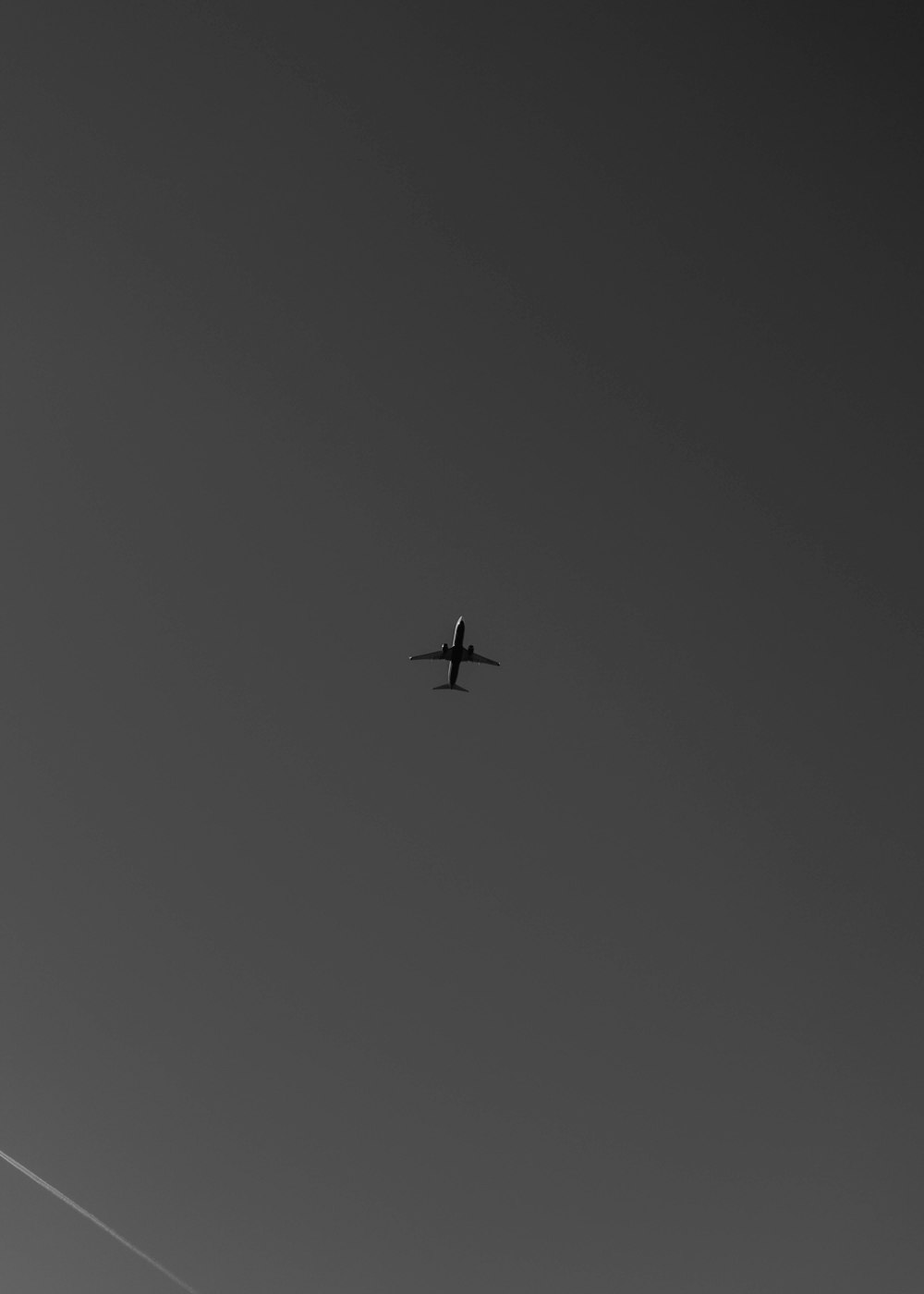 a black and white photo of an airplane in the sky