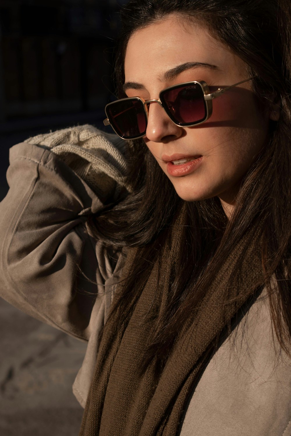 a woman wearing sunglasses and a brown jacket