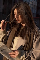 A model wearing a soft knit sweater and stylish sunglasses, smiling in natural sunlight.