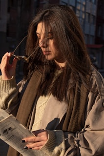 A stylish woman wearing sophisticated glasses, smiling softly in natural light.
