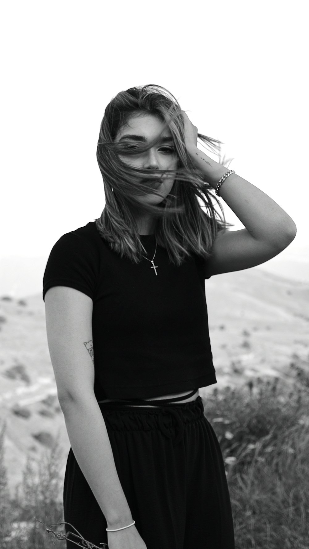 a woman standing in a field with her hair blowing in the wind