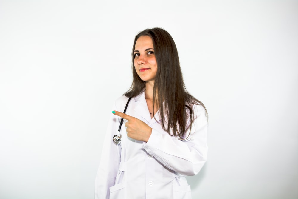 a woman in a white lab coat pointing at something