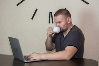 A focused solo founder working late at a minimalist desk with a laptop and a cup of coffee.