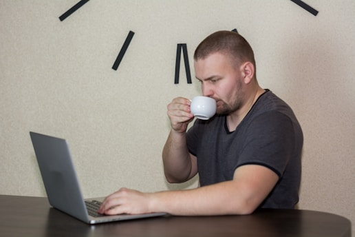 A focused solo founder working late at a minimalist desk with a laptop and a cup of coffee.