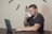 A man working on a laptop with a coffee cup beside him.