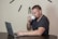 A happy man working on a laptop with a coffee cup.