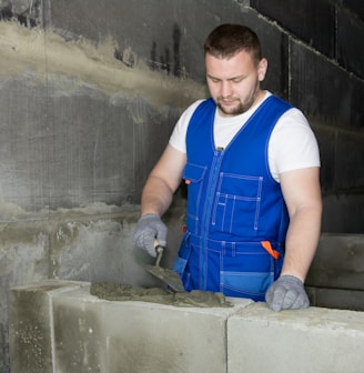a man in blue overalls working on cement