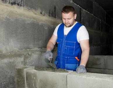 a man in blue overalls working on cement