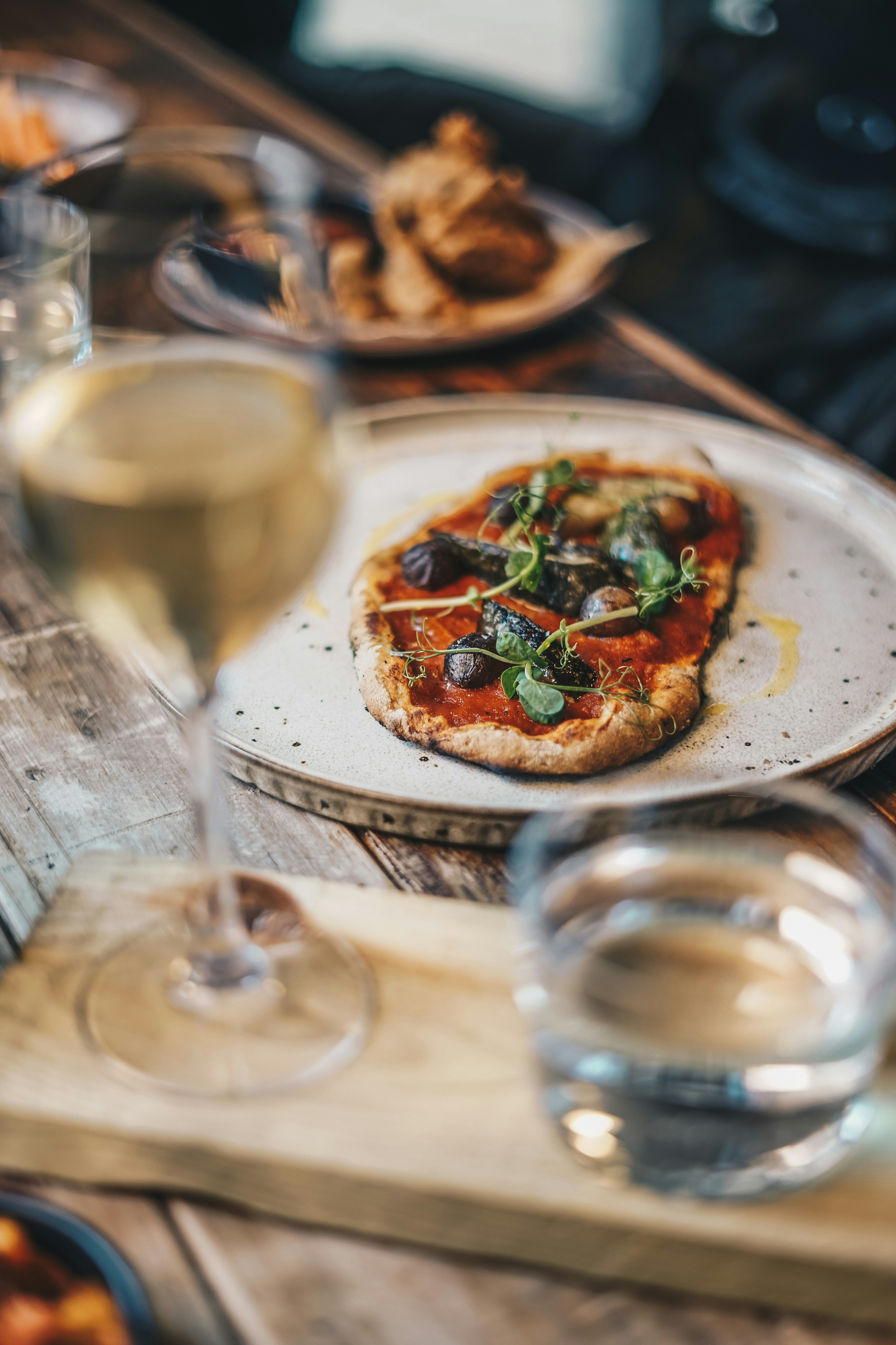 a plate with a pizza on it next to a glass of wine