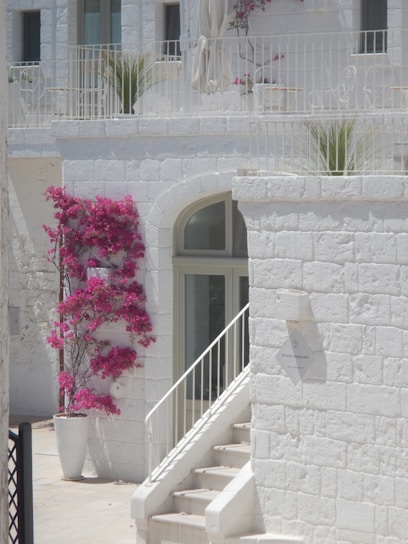 A charming stone facade of a traditional Alaçatı konak with vibrant flowers around the entrance.