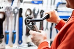 a man holding a wrench in front of a wall of tools