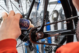 a person holding a bottle of beer near a bicycle