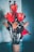 A bouquet of large, red artificial flowers arranged in a brown cylindrical vase. The petals are made of textured material, and the background is softly blurred with gradient shades of blue and gray.