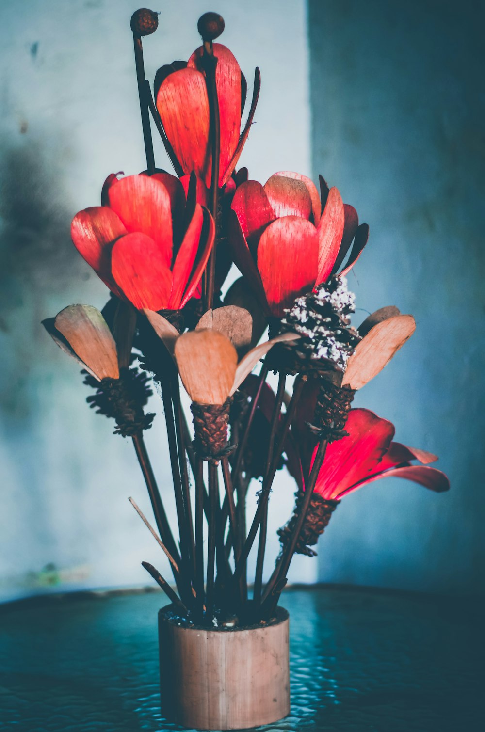 a vase filled with red flowers on top of a table