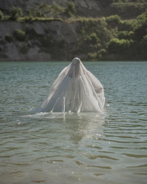 An elven figure cloaked in emerald standing beside a shimmering stream.