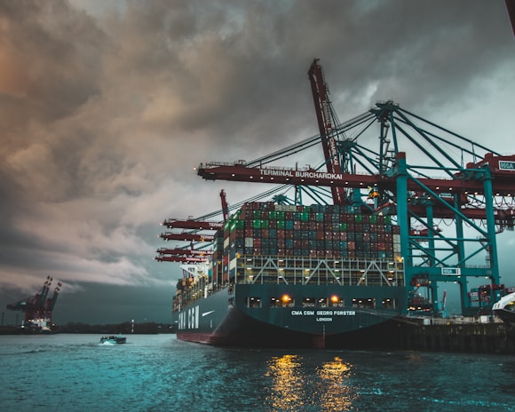 a large cargo ship in a harbor under a cloudy sky