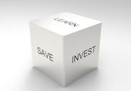 A three-dimensional cube with words on its visible sides, featuring 'LEARN' on the top, 'SAVE' on the left face, and 'INVEST' on the right face. The cube is rendered in a minimalist white and gray color palette, creating a clean and professional look.