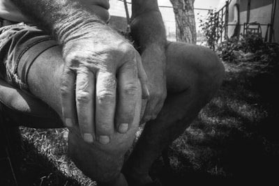 Close-up of an elderly person's hands gently massaging their knee, highlighting joint care.