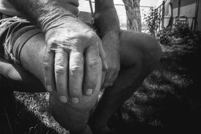 Close-up of weathered hands resting gently on aged knees, telling stories without words.