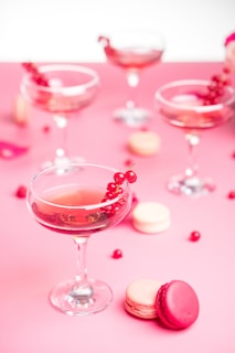 a pink table topped with a wine glass filled with wine