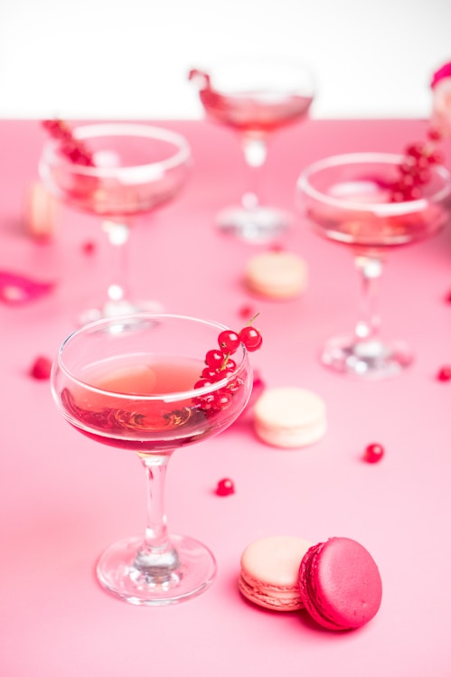 a pink table topped with a wine glass filled with wine