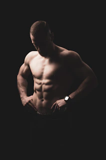 a shirtless man with his hands in his pockets