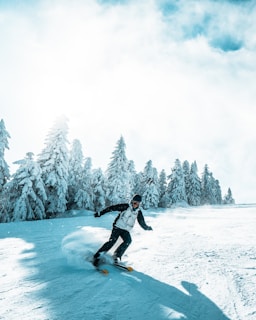 A young athlete skiing down a snowy slope with pine trees in the background