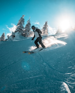 A vibrant winter scene showing a skier gliding down a snowy slope with clear blue skies.