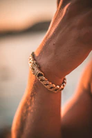 Artisan hands carefully crafting a gold bracelet with fine detailing under warm lighting.